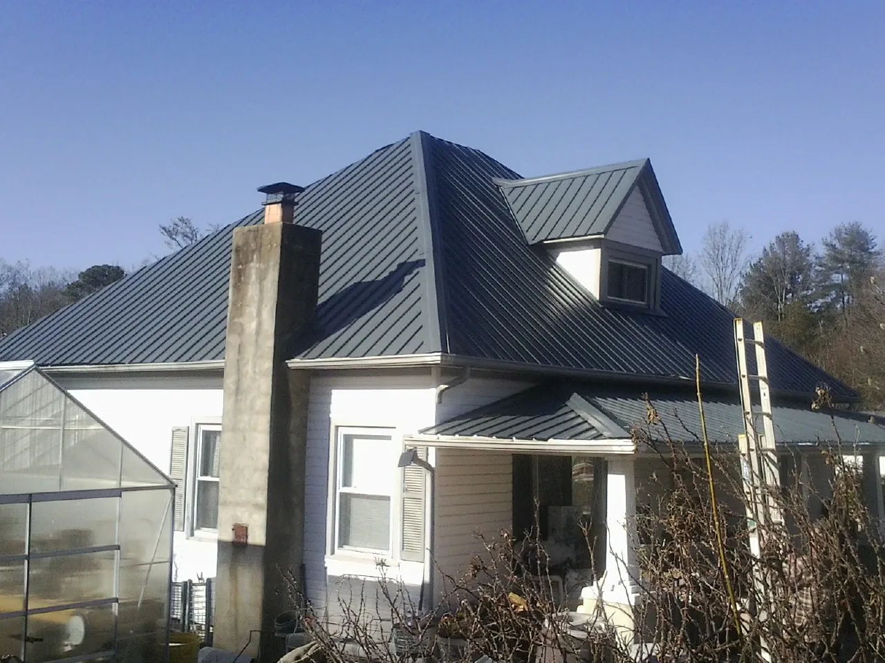 Dark blue standing seam metal roof on a white farmhouse with dormer — Slate & Tile Roof Repair by Roofing Brothers in Mascoutah
