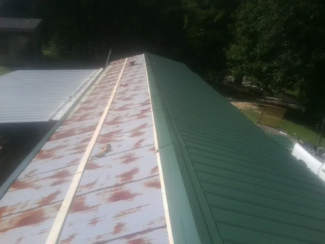 Old rusted panels beside newly installed green metal roofing — Wind Damage Roof Repair by Roofing Brothers in Mascoutah