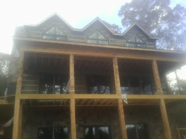 Dormers and porch framing on a large log home under construction — Roof Coating work by our crew in Mascoutah