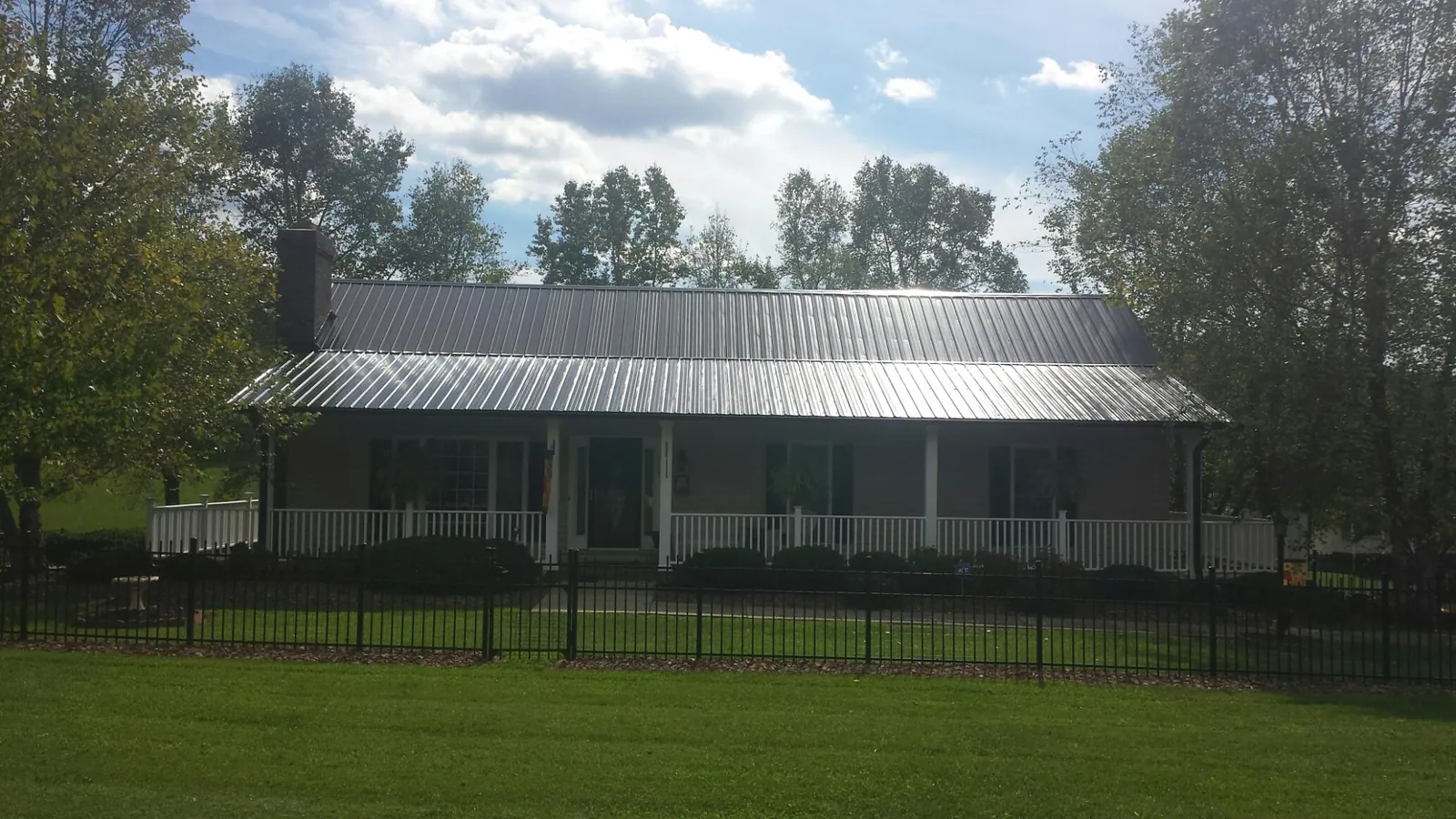 Gray metal roof on a brick ranch with a full width front porch — Gutter Guard Installation work by our crew in Mascoutah