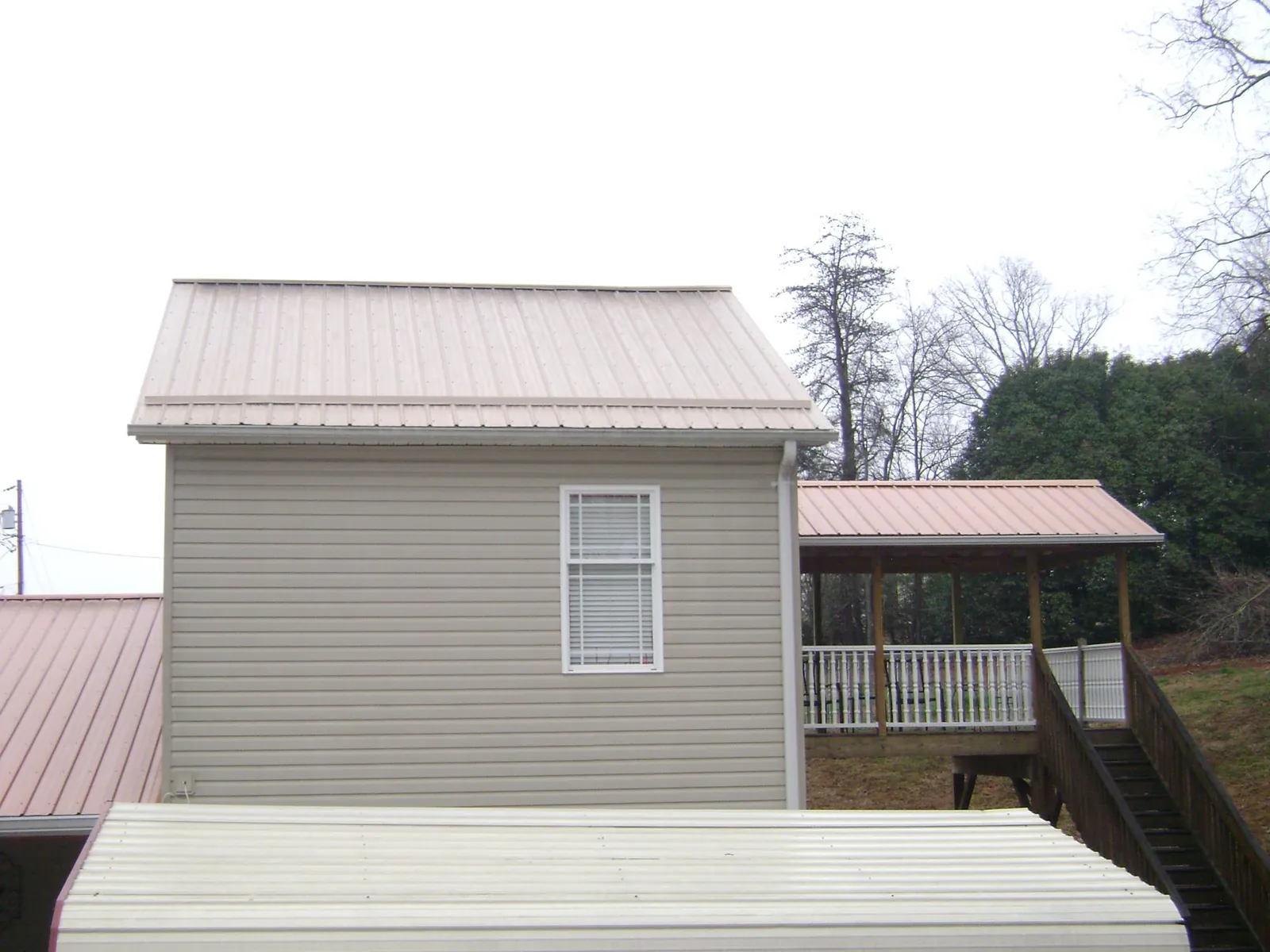 Tan metal roofs on a two story addition and attached porch, from a Roof Replacement job in Mascoutah