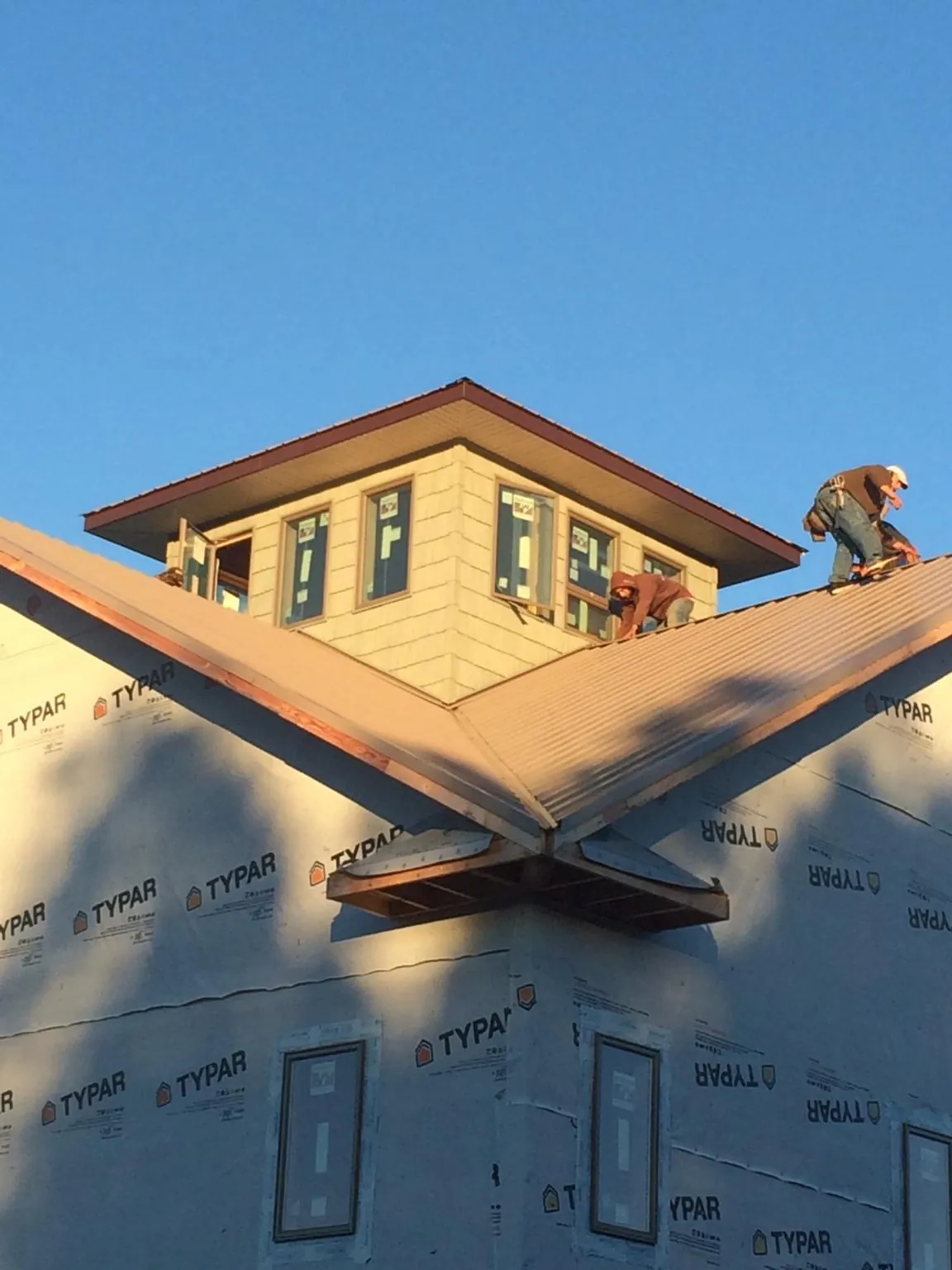 Roofers working around a rooftop cupola on a new metal roof at sunset — Roof Waterproofing in Mascoutah by Roofing Brothers